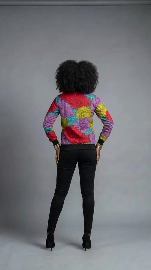 Person wearing a colorful jacket and black pants on a gray background
